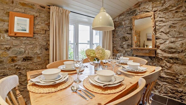 Un espace repas avec un mur en pierre, une table en bois et des chaises.