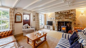 Un salon chaleureux avec une cheminée en pierre, un téléviseur et des fauteuils confortables.
