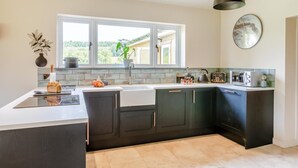 Una cocina moderna con armarios oscuros, un ventanal grande y una lámpara colgante.