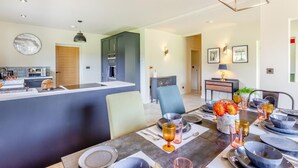 Una cocina moderna con una isla central, comedor con mesa para cuatro personas y sala de estar con sofá y mesa de centro.