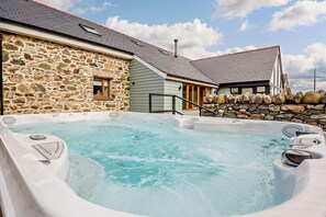 Un bâtiment en pierre doté d’un jacuzzi et d’un mur en pierre.