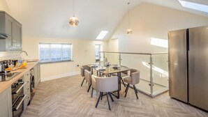 A modern kitchen with a dining area, a large refrigerator, and a skylight. - 2 Bed in Abersoch (oc-r26047) (Abersoch)