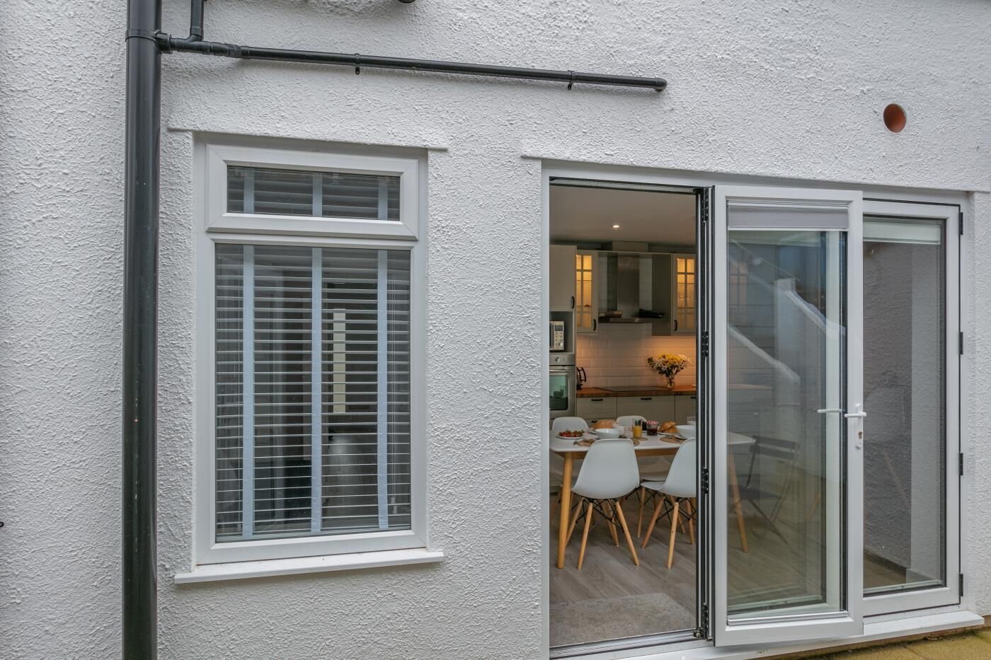 A modern house with a dining area and kitchen visible through a glass door.