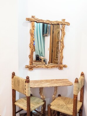 A wooden table with two chairs, a mirror with a wooden frame, and a blue curtain. - PALACIO DEL SOL (Chefchaouen)