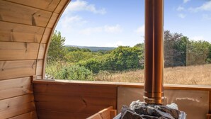 Une cabane en bois dotée d’une grande fenêtre donnant sur un paysage verdoyant.
