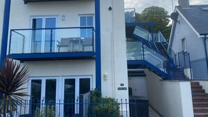 A multi-story residential building with balconies, a staircase, and a door with a sign. - 2 Bed in Penally Near Tenby (oc-g28130) (Penally)