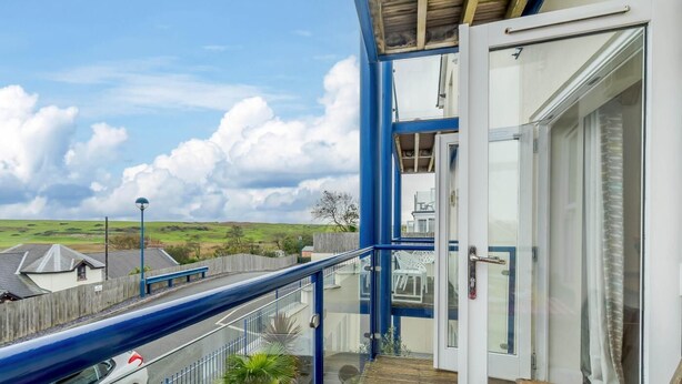 A balcony with a view of the countryside, a wooden fence, and a parked car. - 2 Bed in Penally Near Tenby (oc-g28130) (Penally)