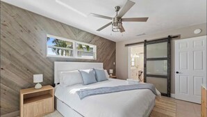Una camera da letto con un letto, comodini, una ventola a soffitto, una finestra e una porta scorrevole.