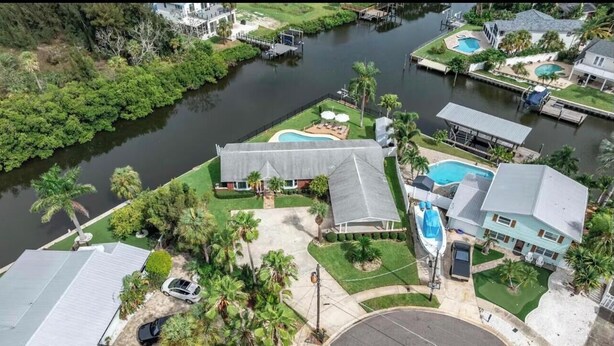 Una proprietà residenziale con piscina, patio coperto e molo che si estende su un fiume.