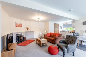 Ein modernes Wohnzimmer mit Kamin, einer Couch, einem Couchtisch und einem roten Pouf.