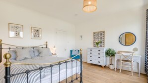 Une chambre à coucher comprenant un lit, une commode, une chaise et un luminaire suspendu.