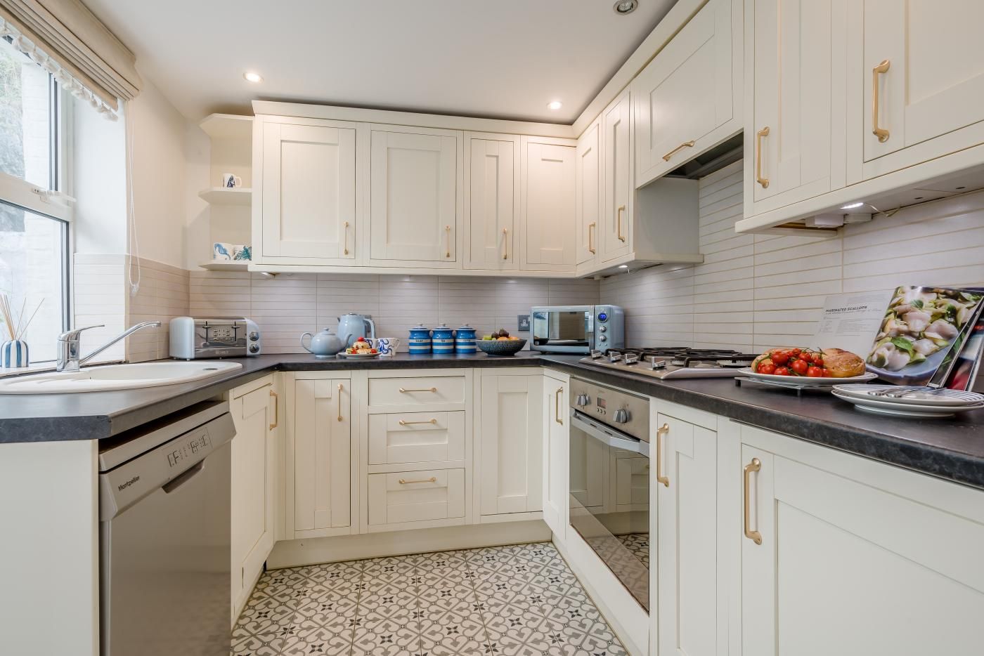 A modern kitchen with white cabinetry, a black countertop, and a tiled backsplash.