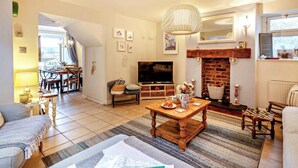Ein gemütliches Wohnzimmer mit Kamin, Fernseher und Essbereich mit Tisch und Stühlen.