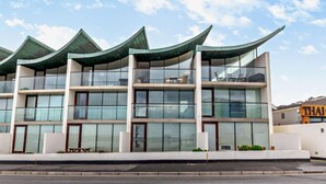 Un edificio moderno de varios pisos con un diseño de techo curvo, ventanas amplias y fachada plana.