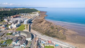 Vista aérea de un pueblo costero con playa, edificios y un estadio.