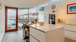 Una cocina moderna con una isla grande, horno empotrado y vistas del entorno.