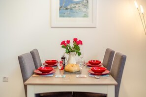 A dining table set with red bowls, a pitcher of flowers, and a loaf of bread. - 2 Bed in Fowey (oc-s25324) (Fowey)