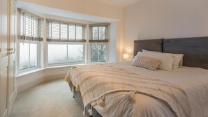 A bedroom with a large bed, a window with blinds, a nightstand with a lamp, and a wardrobe. - 5 Bed in Mynytho (oc-c28916) (Mynytho)