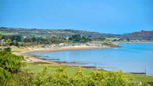 A coastal area with a beach, houses, and greenery. - 5 Bed in Mynytho (oc-c28916) (Mynytho)