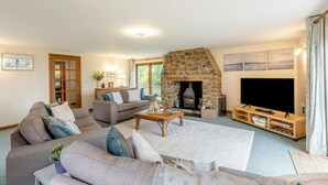 Ein Wohnzimmer mit Kamin aus Stein, einer Sofagarnitur, einem Couchtisch, einem Flachbildfernseher und einer Holzunterhaltungseinheit.