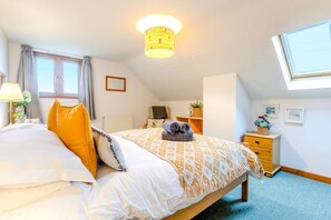 Une chambre à coucher comprenant un lit, un bureau, une chaise, un radiateur, une fenêtre et un luminaire au plafond.