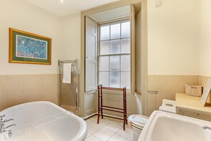 Een badkamer met een bad, toilet en een raam met glas-in-lood.
