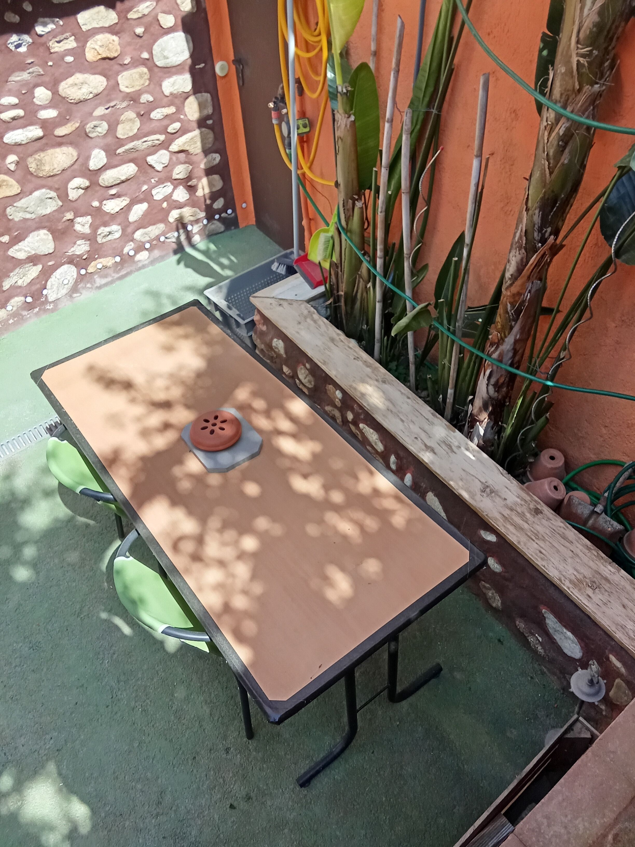 Une table avec une pastèque, une chaise verte et un banc.