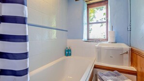 A bathroom with a bathtub, a window, and a toilet. - 3 Bed in Mortehoe (oc-s29000) (Woolacombe)