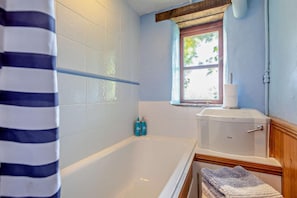 A bathroom with a bathtub, a window, and a toilet. - 3 Bed in Mortehoe (oc-s29000) (Woolacombe)