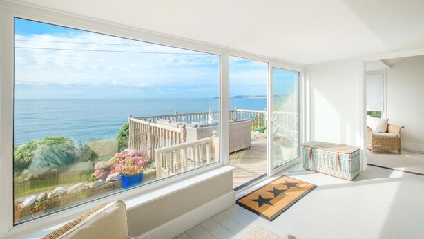 Een balkon met uitzicht op zee, een rieten mand en een deurmat.