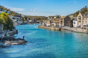 Un pueblo costero con río, edificios de piedra y un muelle.