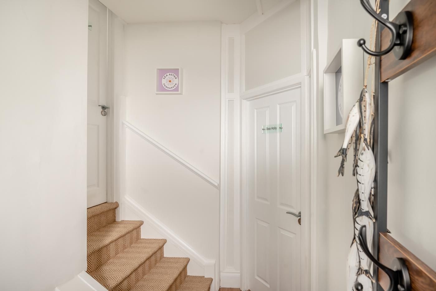 A staircase with a wooden handrail, a white door, and a wall-mounted fish decoration.