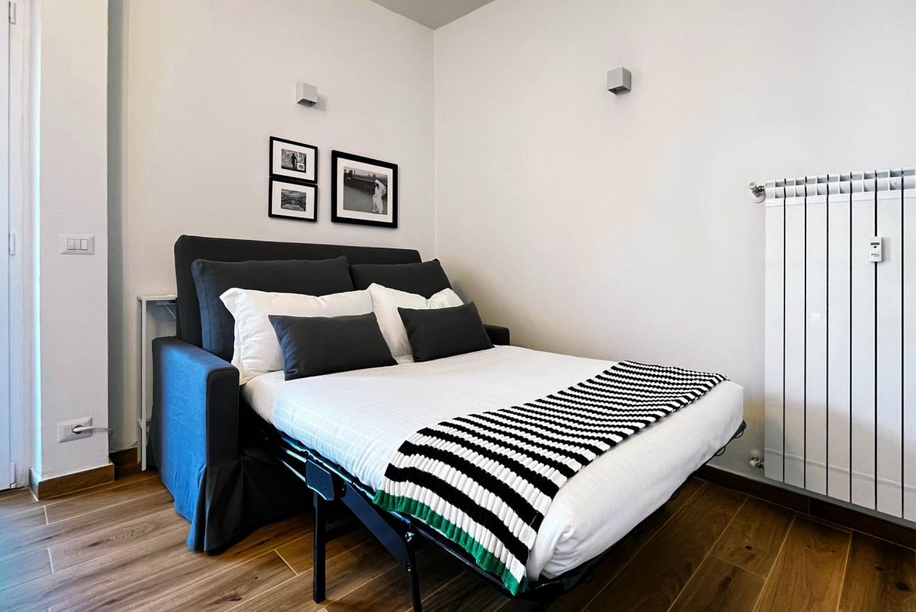 Une chambre à coucher moderne, avec un lit, une tête de lit, une table de chevet et un radiateur.