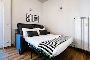 A modern bedroom with a bed, a headboard, a bedside table, and a radiator. - Alma Suites - Terrace Penthouse (Firenze)