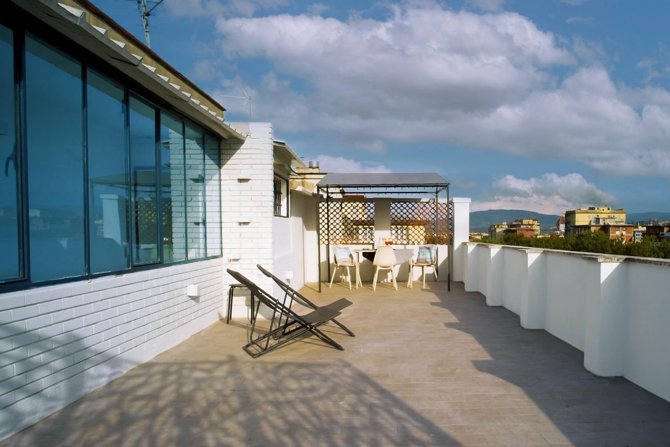 A rooftop terrace with a dining area, a pergola, and a view of the cityscape.