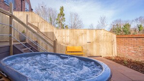 Ein Whirlpool in einer hölzernen Außenbereich mit einer Holztreppe und einer gelben Bank.