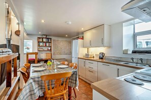 A modern kitchen with a dining area, featuring a stove, sink, and a bookshelf. - 2 Bed in Grisedale (oc-c29159) (Grisdale)