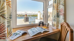 A room with a wooden desk, open books, binoculars, and a view of a harbor with boats. - 2 Bed in Polruan (oc-denzil) (Fowey)