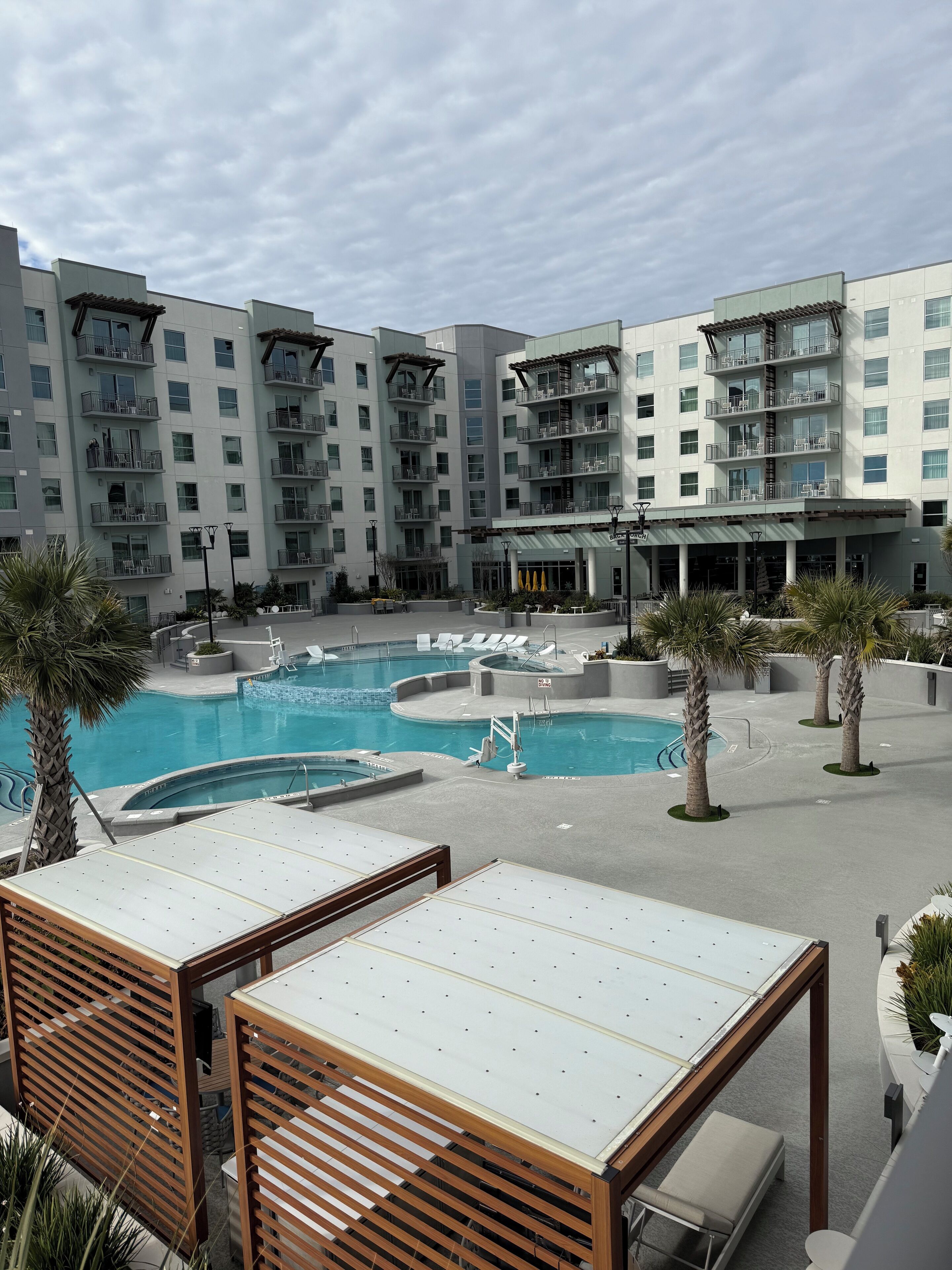 Un hôtel doté de nombreux balcons, d’une piscine et d’espaces de détente avec des chaises longues.