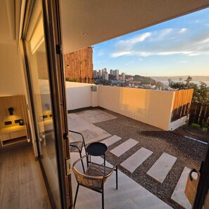 Un balcón con vista a la ciudad, una zona de estar con un banco y una valla de madera.