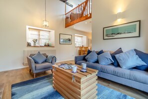 A modern living room with a sofa, a coffee table, and a dining area with chairs. - 2 Bed in Langham (oc-g25208) (Langham)