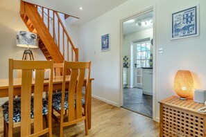 A dining area with wooden chairs and a table, a staircase, and a kitchen visible through an open door. - 2 Bed in Langham (oc-g25208) (Langham)
