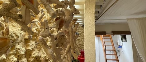 Quarto com parede texturizada, escada e um balde vermelho.