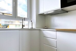 A modern kitchen with white cabinets, a stainless steel sink, and a window overlooking a balcony. - Alma Suites - Skyline Penthouse (Firenze)