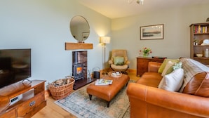 A cozy living room with a fireplace, leather sofa, and a television. - 2 Bed in Pencaenewydd (oc-t29187) (Pencaenewydd)