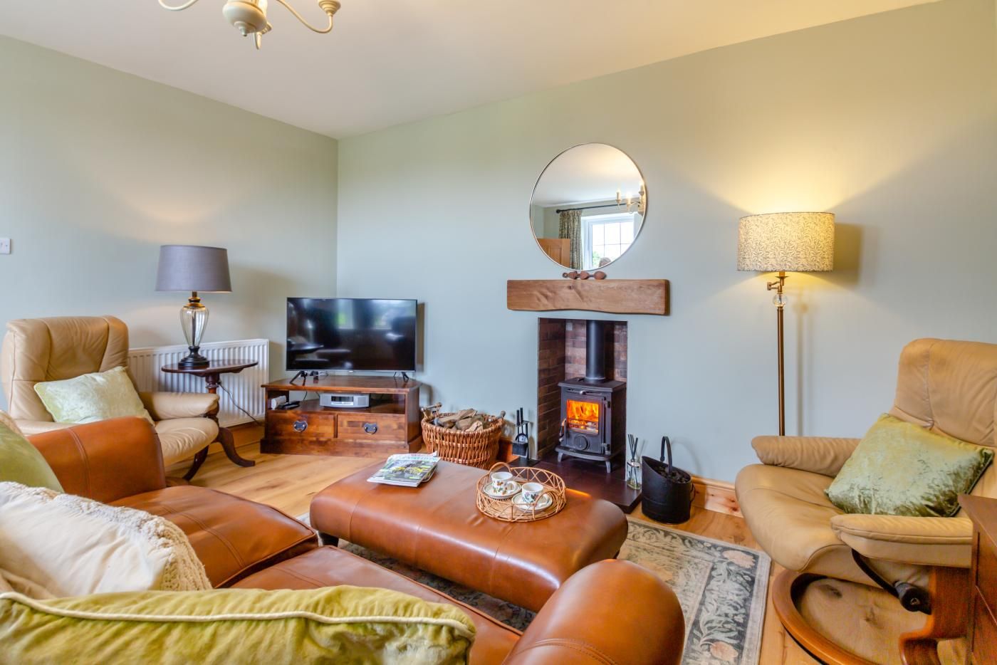 A living room with leather sofas, a television, a fireplace, and a mirror on the wall.