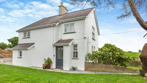 A two-story house with a dark front door, a small porch, and a brick wall. - 2 Bed in Pencaenewydd (oc-t29187) (Pencaenewydd)