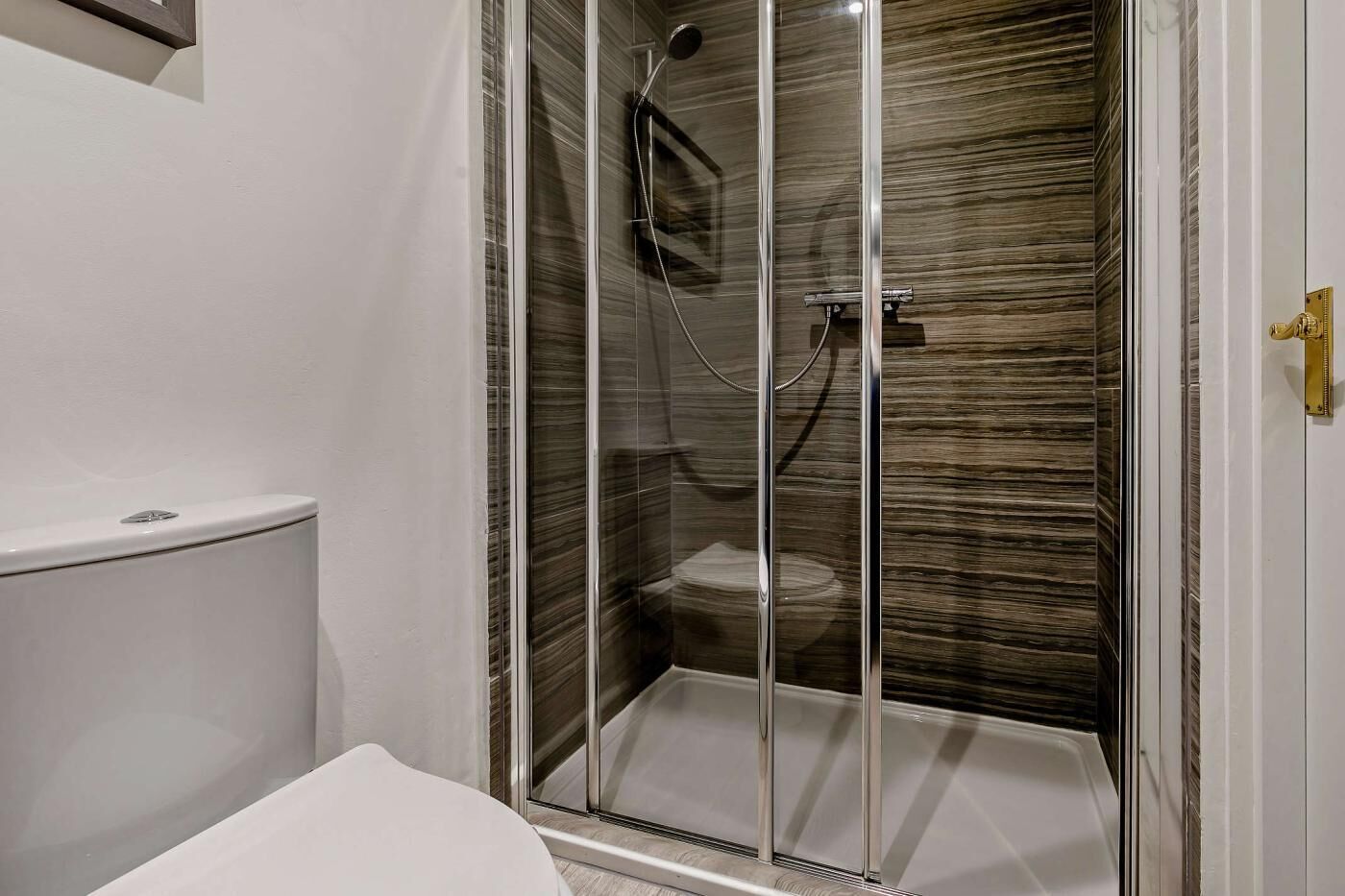 A bathroom with a glass-enclosed shower, a toilet, and a white sink.