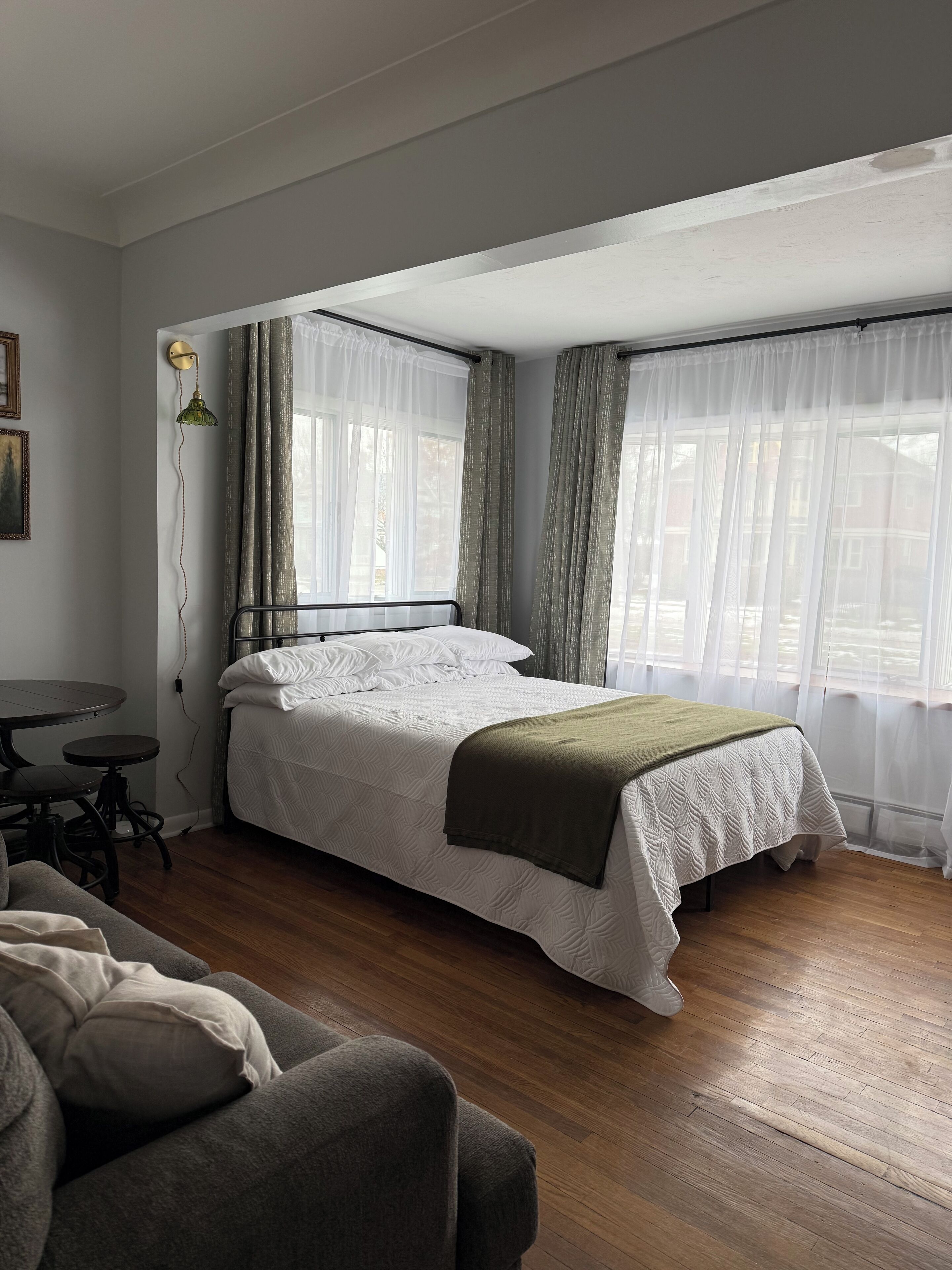 A neatly arranged bedroom with a bed, a small table, and a couch.