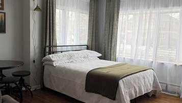 A neatly arranged bedroom with a bed, a small table, and a couch.